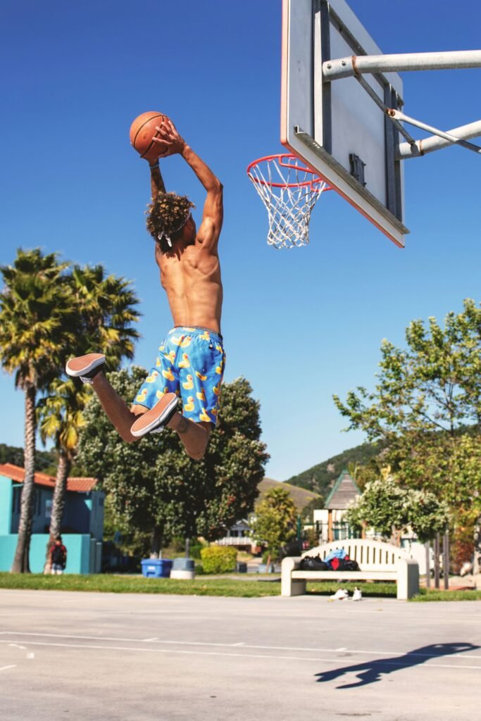 young player in a basketball game jumping for the ball during a match at sunset.